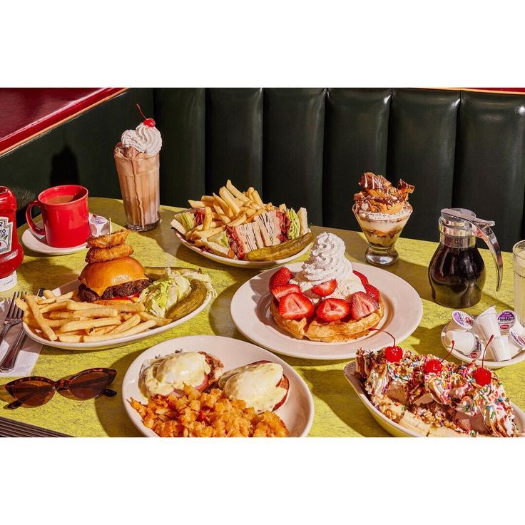 a table topped with plates of food next to cups of drinks and glasses filled with ice cream