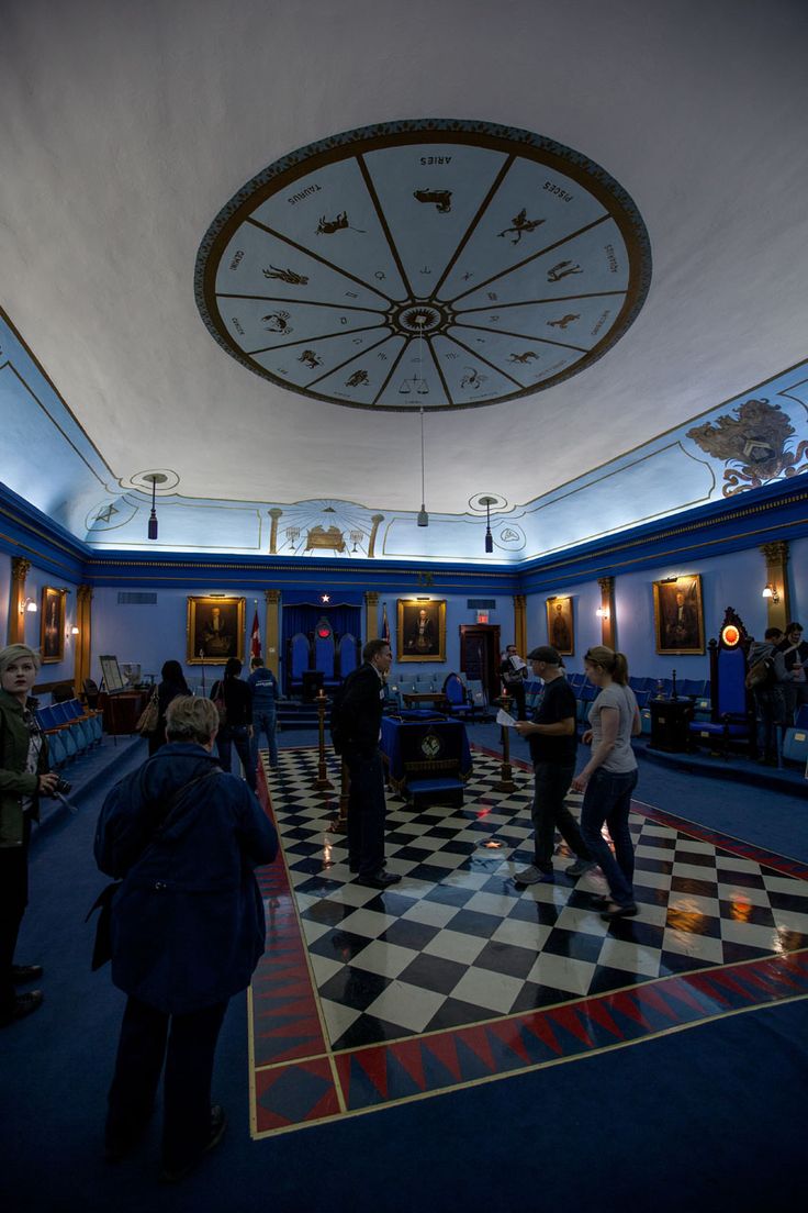 several people are standing in a room with checkered flooring and blue walls on the ceiling