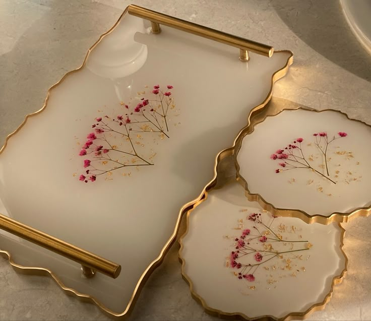 three plates with flowers on them sitting on a counter top next to a cup and saucer