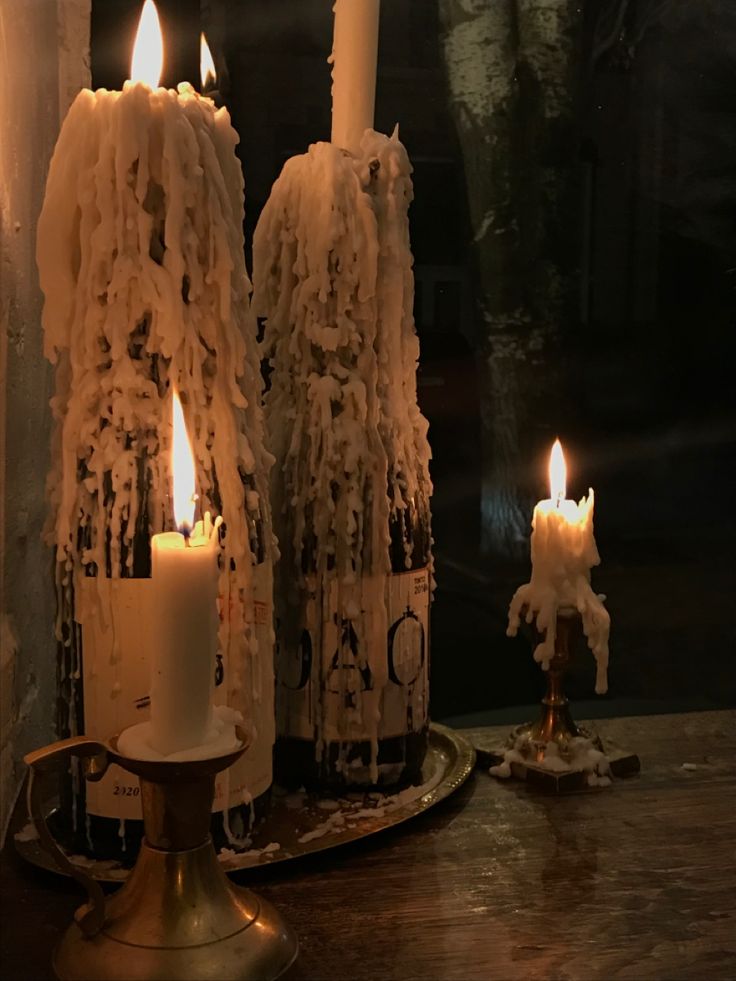 three lit candles sitting on top of a table next to a candle holder with icing