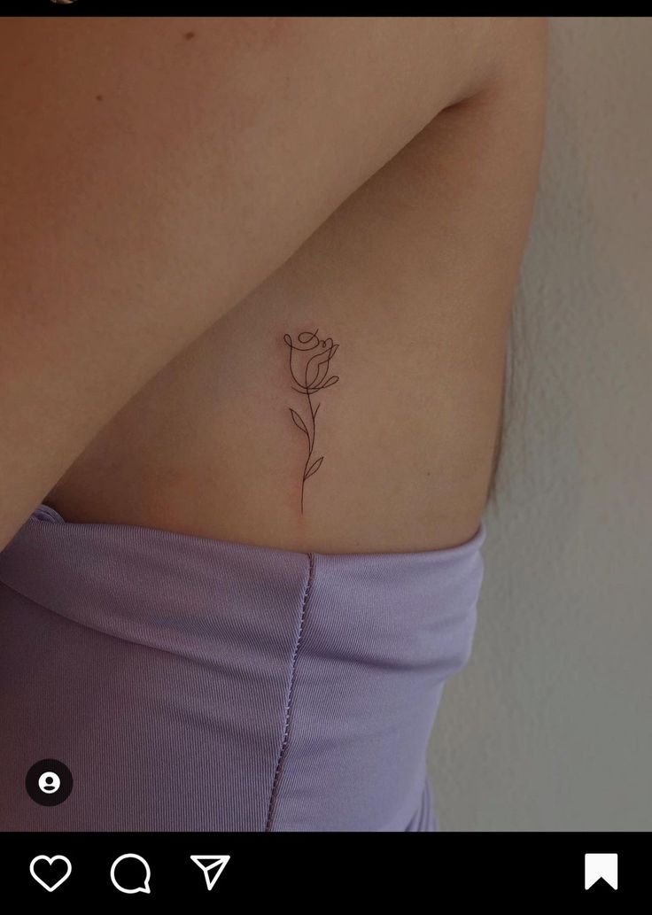 a woman's stomach with a single rose tattoo on her left side ribcage