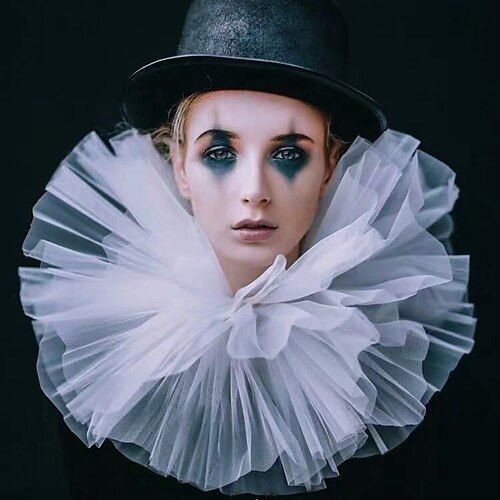 a woman with black makeup and white tulle around her neck wearing a top hat