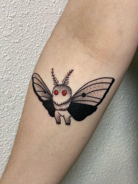 a small tattoo on the arm of a person with a black and white moth design