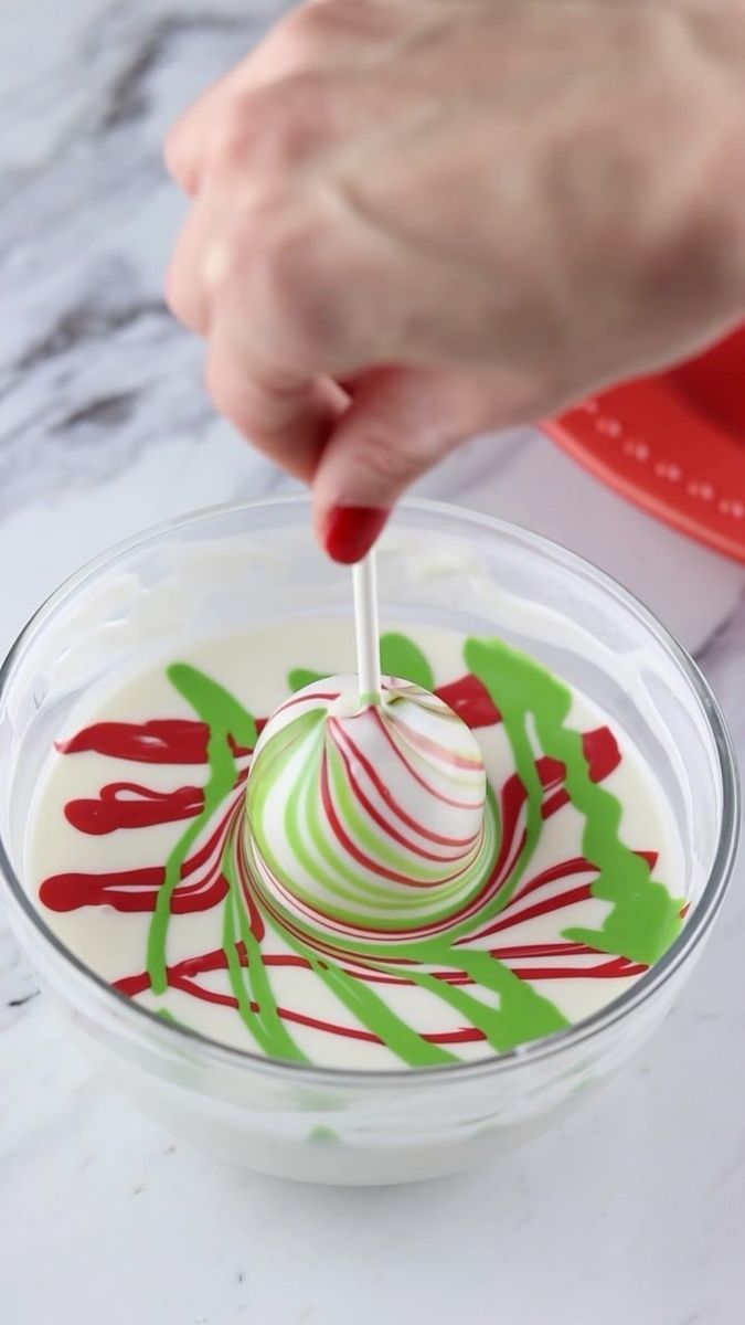 someone is dipping some kind of candy into a bowl with green and red swirls