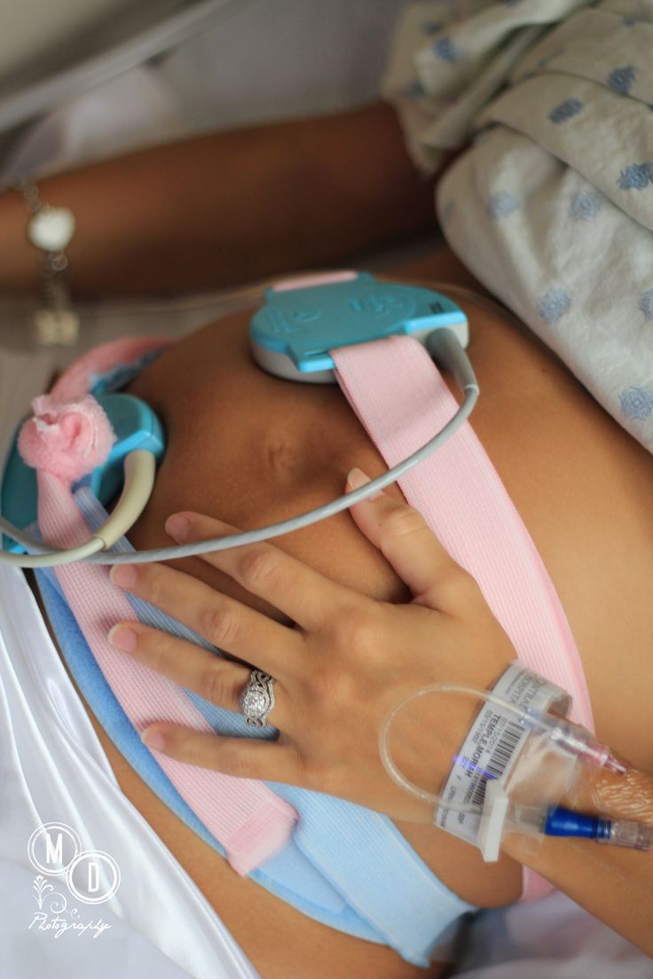 a pregnant woman in a hospital bed with an iv tube attached to her stomach and wearing a pink bra