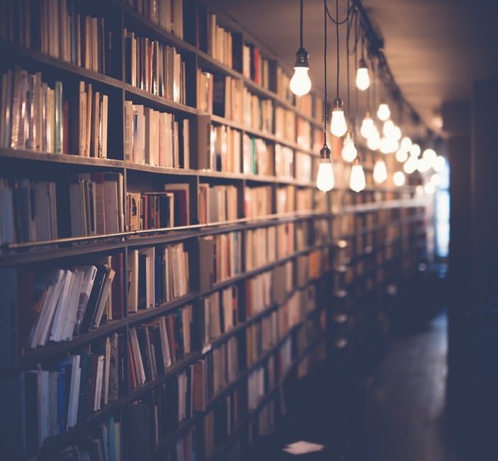 a book shelf filled with lots of books next to a light bulb hanging from the ceiling