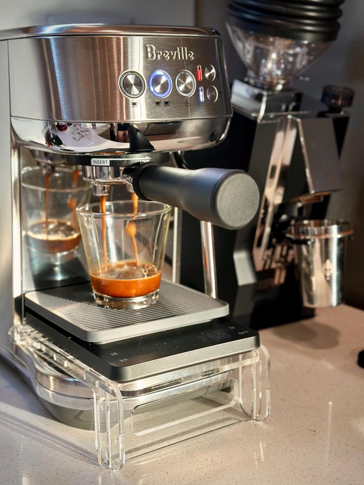 an espresso machine is being used to make coffee and orange juice on the counter