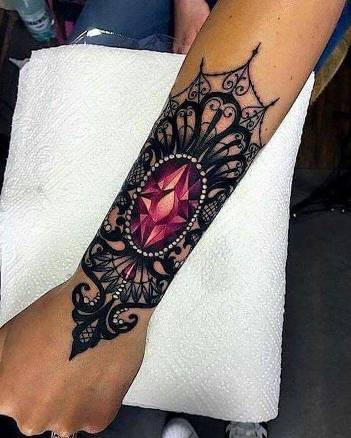 a woman's foot with a tattoo on it and a pink stone in the center