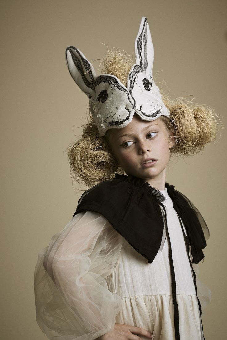 a woman wearing a mask with two rabbits on it's head and hair blowing in the wind