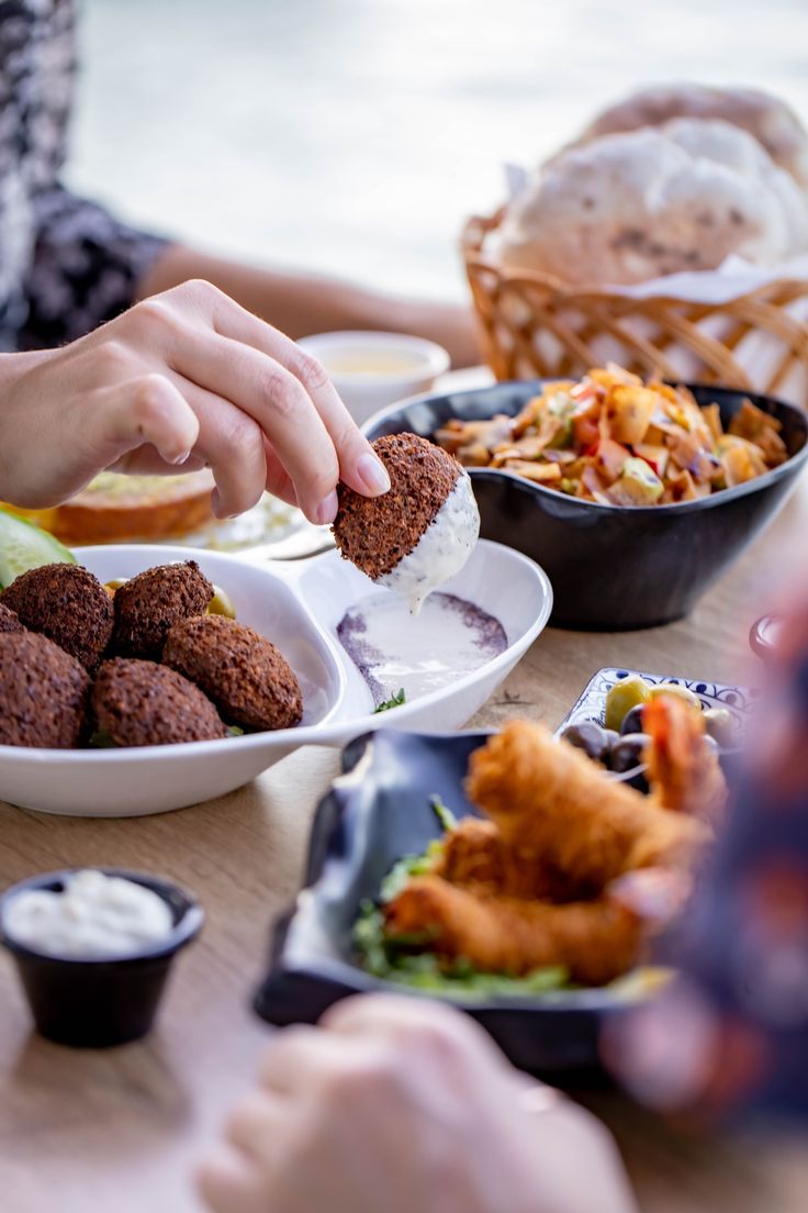 people sitting at a table eating food and dipping sauces on their fingers to eat them