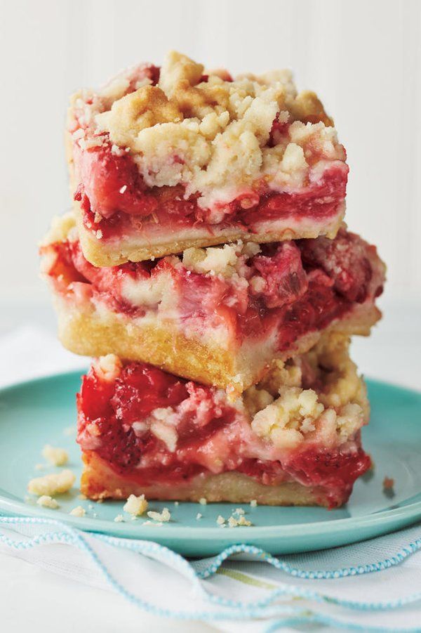 three pieces of strawberry crumbler bars stacked on top of each other in a blue plate