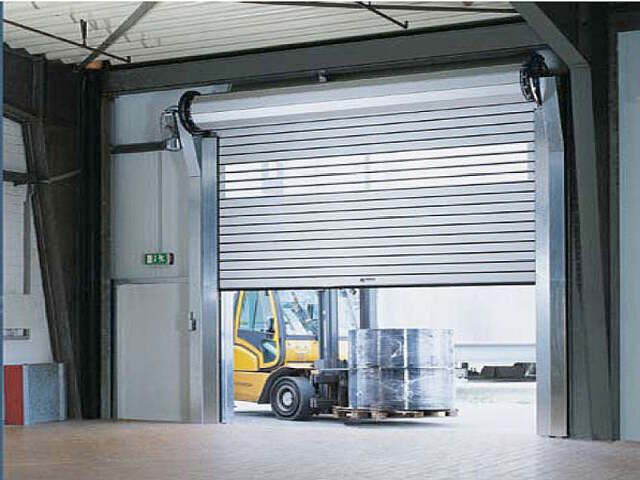 a semi truck is parked in front of a garage door that has roller up doors