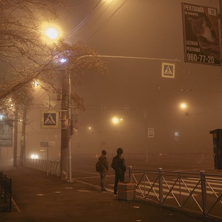 two people walking down a foggy street at night