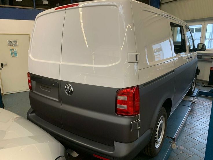 the back end of a van parked in a garage next to other cars and trucks