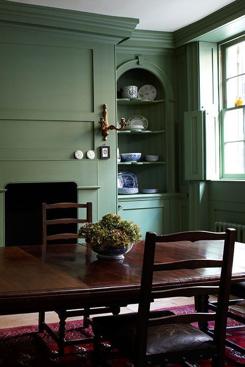 a dining room with green walls and wooden table