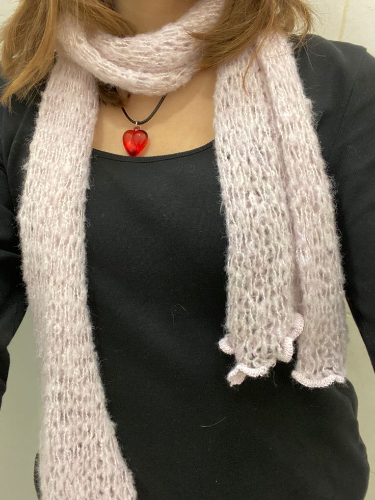 a woman wearing a black shirt and white scarf with a red heart on it's lap