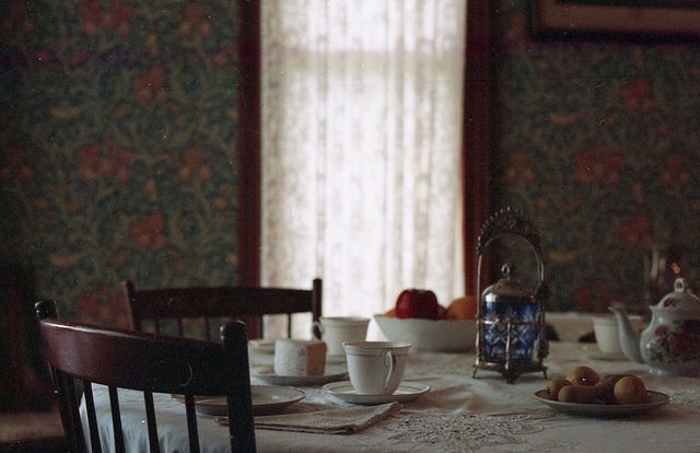 a dining room table with plates and cups on it, next to a tea kettle