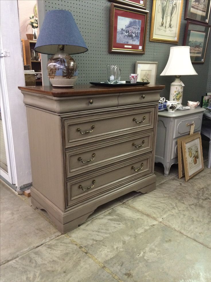 an antique dresser is displayed in a room with pictures on the wall and lamps on either side