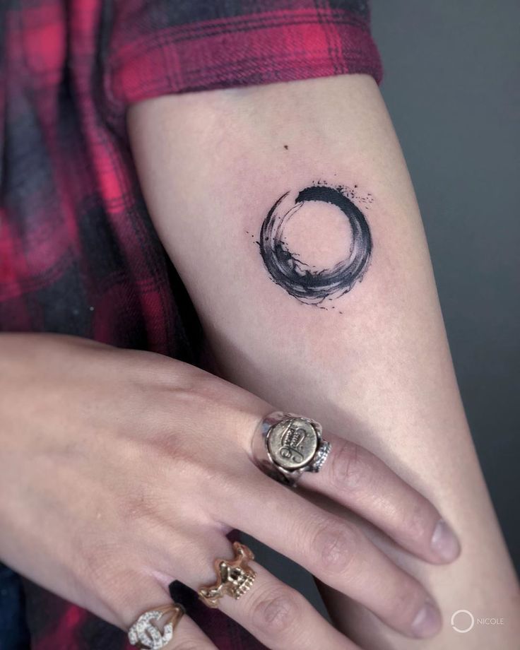 a woman's hand with a tattoo on her left arm and the letter o in black ink