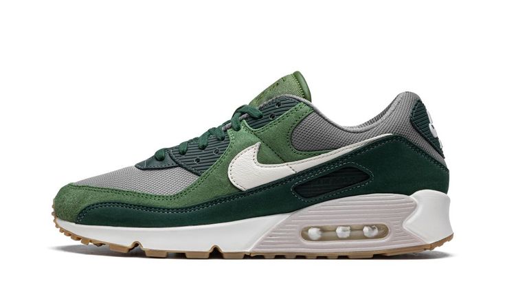 The Nike Air Max 1 “Pro Green” is an earth-tone-inspired colorway included in Nike’s Spring/Summer 2022 release cycle.  In “Pro Green & Pale Ivory,” the Air Max 90 sheds its performance based roots and enters the lifestyle category with plush light and dark green suede overlays against a grey mesh base.  A white leather Swoosh logo appears on both sides of the shoe.  Classic “Nike Air” branding is found on the heel, and a tonal “Air Max” branding window appears on the lateral side of the shoe. Nike Air Max 90 Green, Ivory Shoes, Sneakers Nike Air Max, Nike Shoes Girls, Grey Panels, Going Green, Stadium Goods, Mens Nike Air, Swoosh Logo