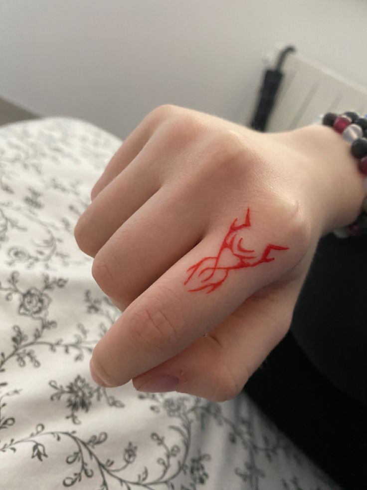 a woman's hand with a red tattoo on it