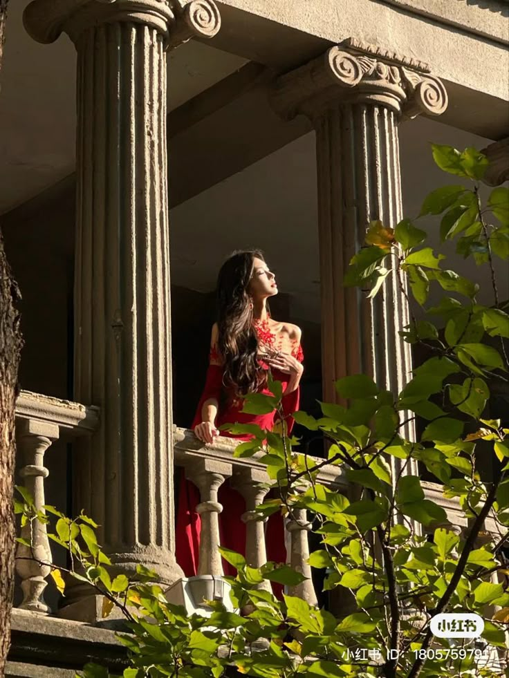 a woman in a red dress standing on a balcony