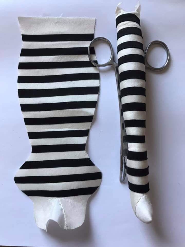 a pair of scissors sitting on top of a black and white striped piece of cloth