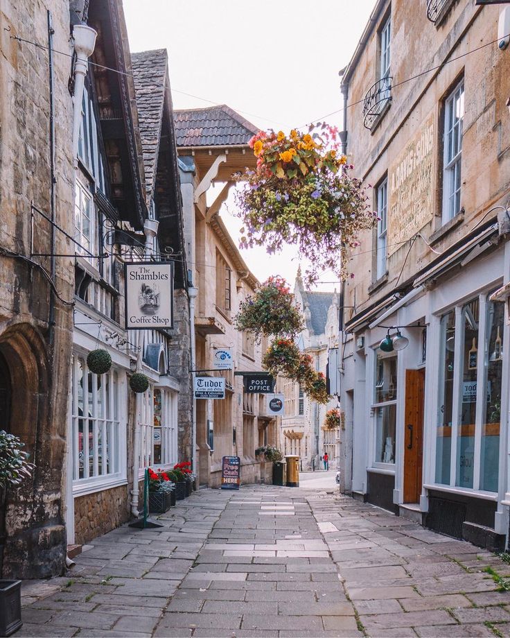 an empty street with shops on both sides and flowers hanging from the buildings in front