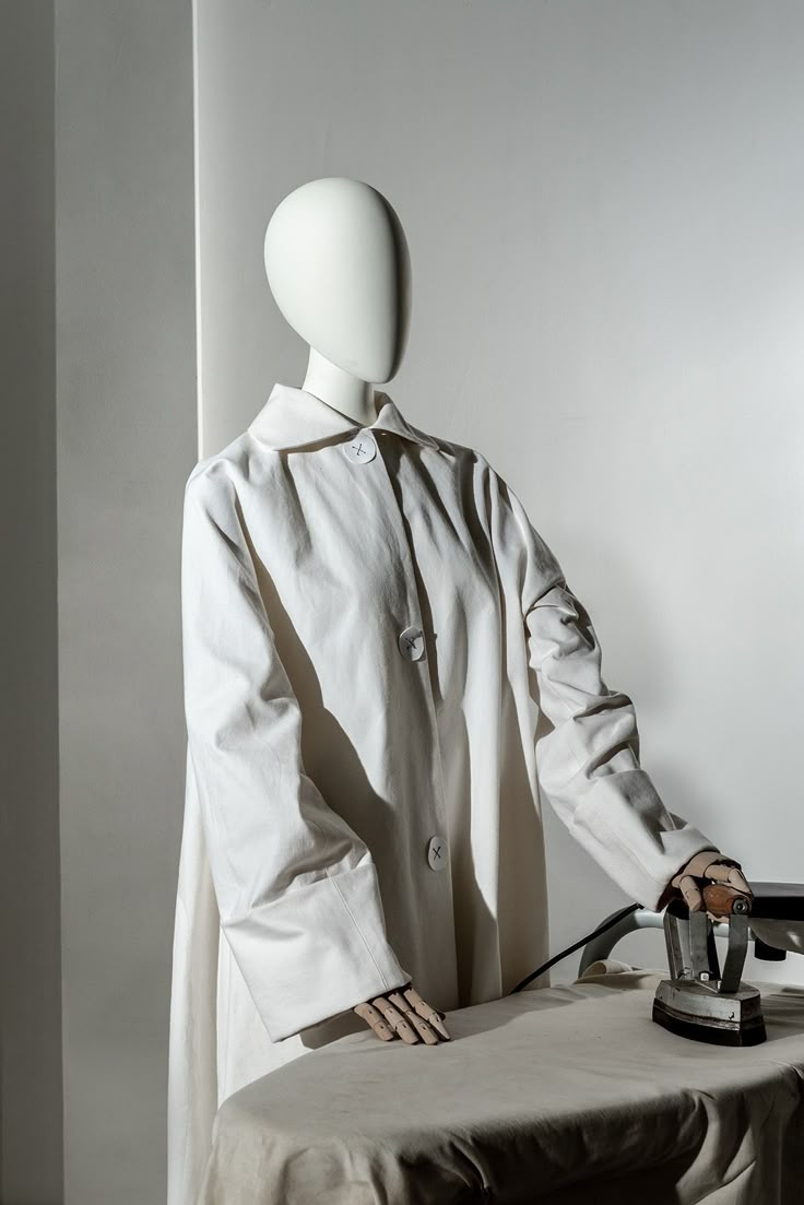 a mannequin is standing next to a table with an iron in it's hands