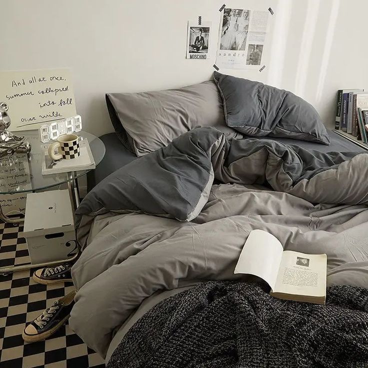 an unmade bed with a book on it in a room filled with books and pictures