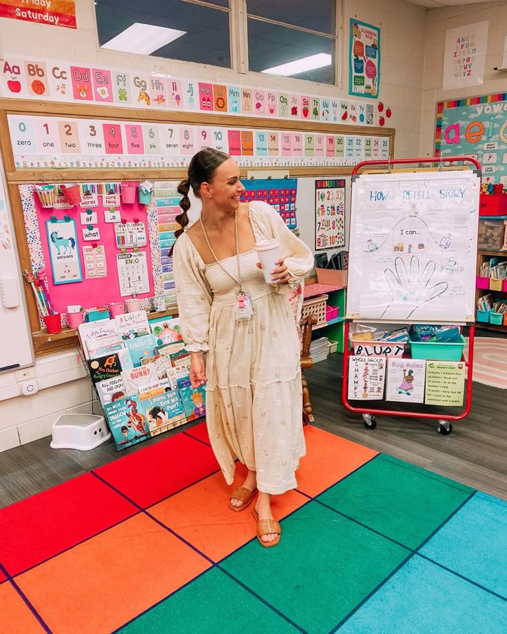 a woman standing in front of a whiteboard with writing on it and holding a cup