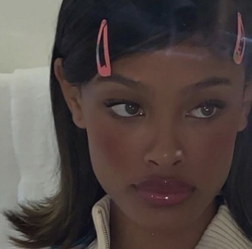 a woman with two pink clips on her head is looking at the camera while wearing a sweater