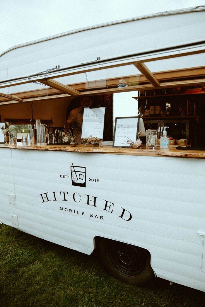 a food truck parked on the grass with its door open and shelves full of items