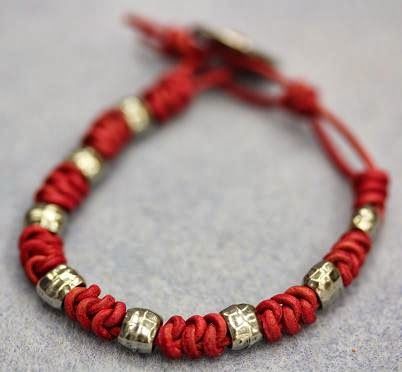 a red string bracelet with silver beads