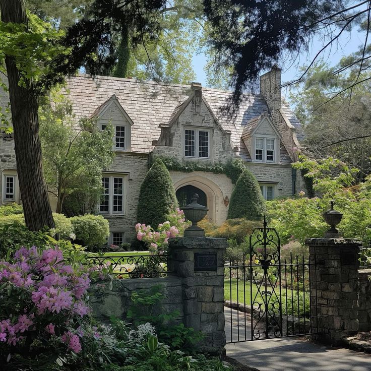 a large house with an iron gate in front of it and lots of flowers around the entrance