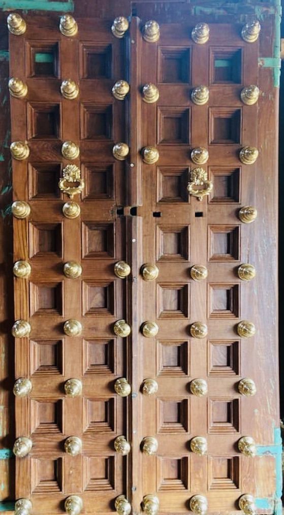 two wooden doors with gold knobs on them and one door has many holes in it