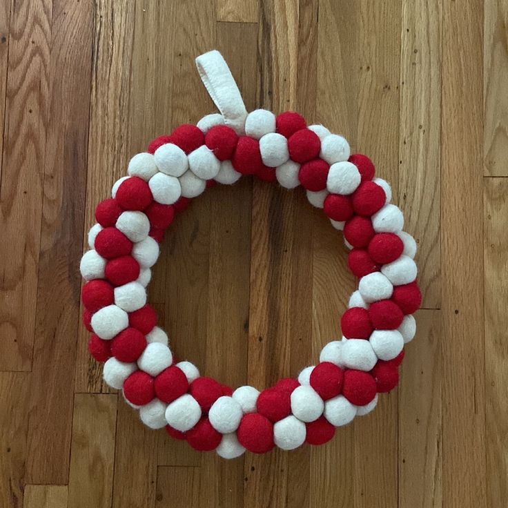 a red and white wreath with pom - poms