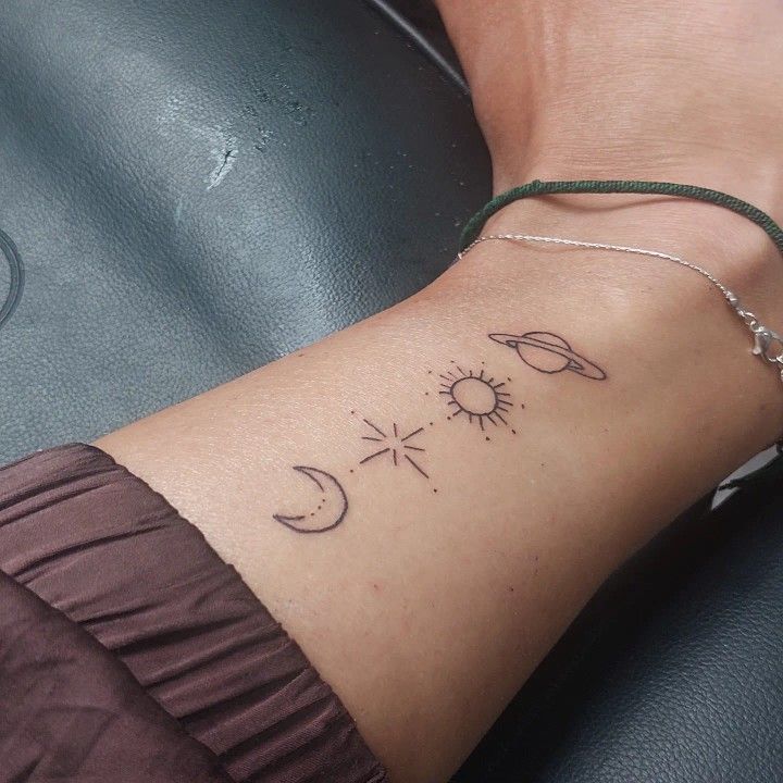 a woman's arm with the sun, moon and stars tattoo design on it