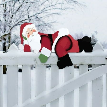 a santa clause doll laying on top of a white fence