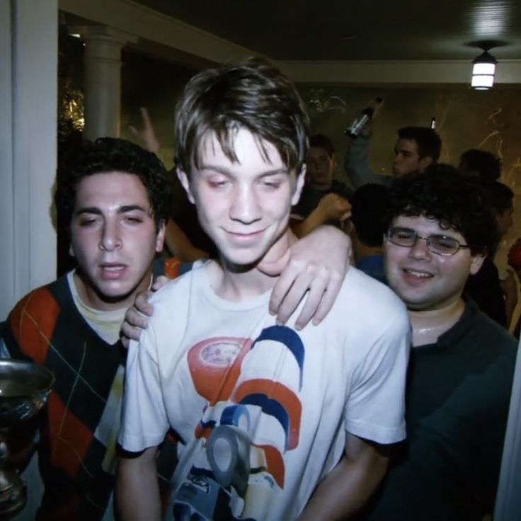 two young men hugging each other in front of a group of people with glasses on