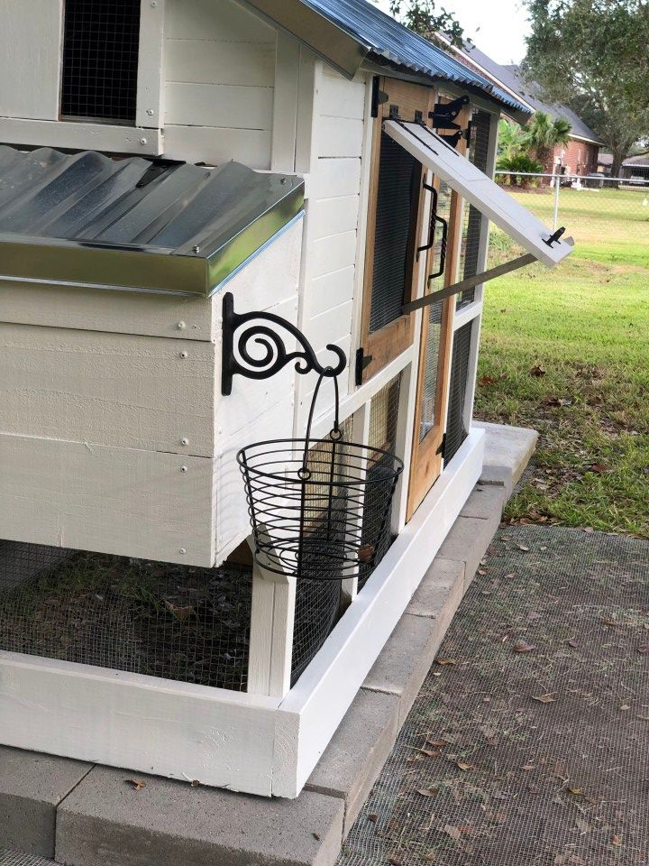 a chicken coop with a metal basket on the door and an antenna attached to it