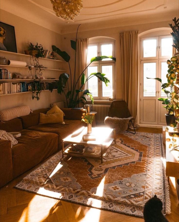 a living room filled with lots of furniture and plants on top of a wooden floor