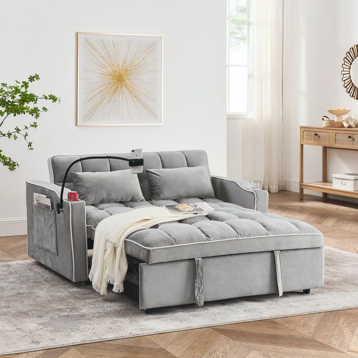 a living room with a gray couch and white rugs on the hardwood flooring