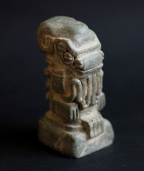 a stone statue is sitting on a black surface