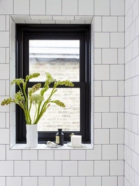 a vase with flowers in it sitting on a window sill next to a brick wall