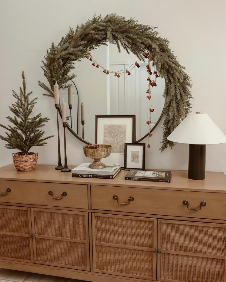 a wooden dresser topped with a mirror next to a lamp