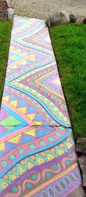 a sidewalk painted with different colors and patterns in the grass next to some stone steps