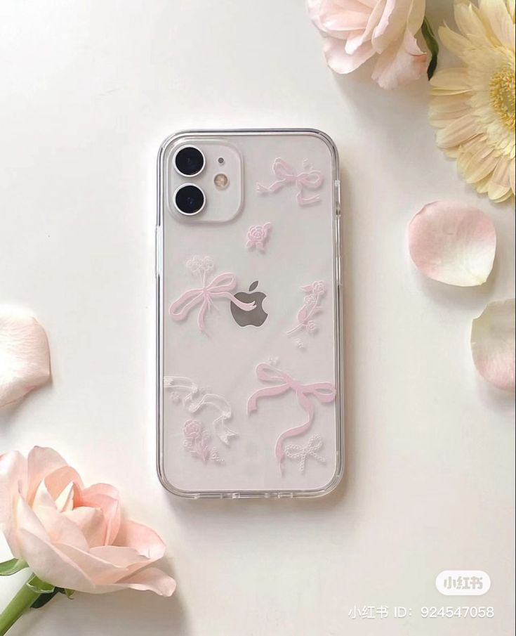 an iphone case with pink bows and flowers on the back, sitting next to it