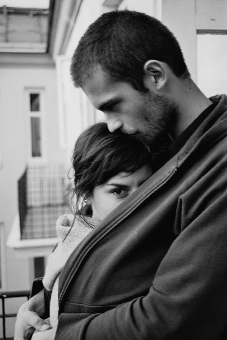 a man and woman embracing each other in black and white