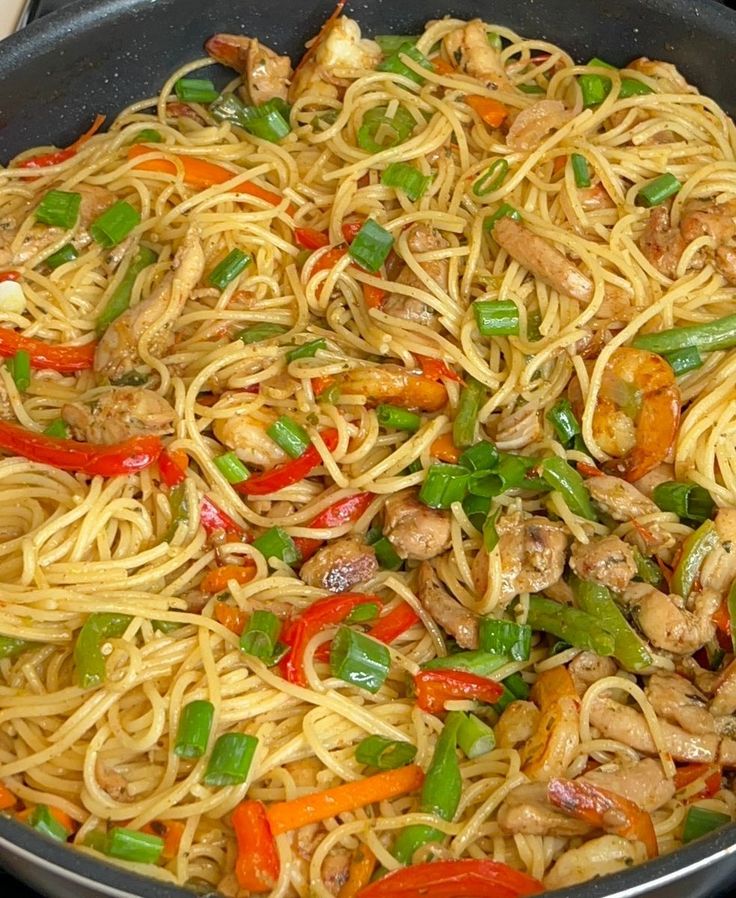 a pan filled with noodles and vegetables on top of a stove